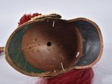 an old helmet with a red wig on top of a white surface