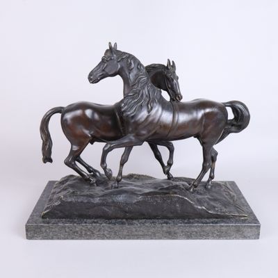 statue en bronze représentant deux chevaux au galop, posée sur un socle en marbre