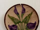 une photo d'une fleur violette et verte posée sur une assiette marron