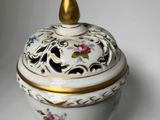 a white bowl with a gold lid on a white surface
