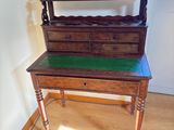 a wooden desk with a green top in the corner of a room