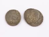 two silver coins sitting next to each other on a white surface
