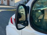 une camionnette blanche garée devant une maison, avec un chien à la fenêtre