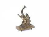 figurine en laiton représentant un poisson, posée sur un socle, sur fond blanc
