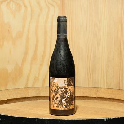 a bottle of wine sitting on top of a wooden barrel