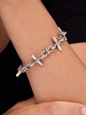 un bracelet en argent en forme de croix au poignet d'une femme