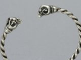 silver bracelet with a twisted design and a skull on the side