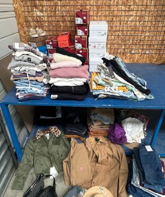 une table bleue sur laquelle sont posés de nombreux vêtements et chapeaux