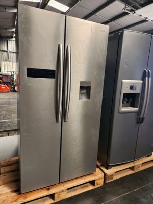 two large stainless steel refrigerators sitting on pallets in a warehouse
