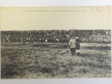 an old photo of two men standing in a field with a crowd of people in the background