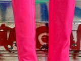 une paire de bottes roses à talons hauts posée par terre devant un mur recouvert de graffitis