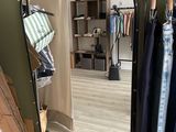 a mirror in the corner of a room with clothes on racks