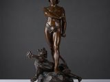 une statue en bronze représentant un homme avec un chien, assis sur un rocher