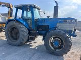 a blue tractor that is parked in the dirt
