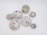 une image représentant un ensemble d'assiettes et de tasses en porcelaine posées sur une surface blanche
