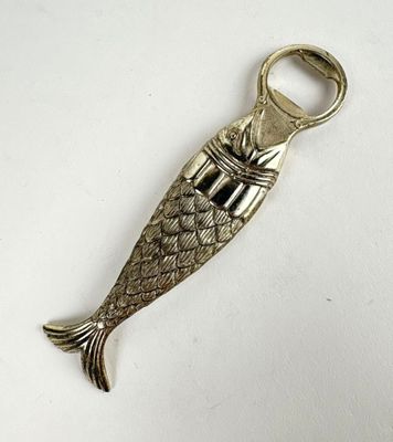 silver fish shaped bottle opener with a metal handle on a white surface