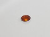 an oval shaped orange sapphire stone on a white surface