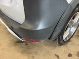 the rear end of a car with a dent on it ' s bumper