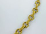 gros plan d'un bracelet en chaîne en or sur une surface blanche