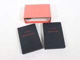 trois livres dans un coffret rouge et noir posé sur une surface blanche