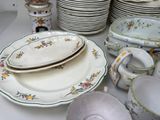 many plates and bowls on the table with cups and saucers
