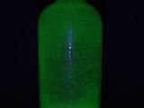 a green glass bottle with a black light in the background