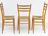 three wooden chairs sitting next to each other on a white surface