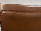 brown leather couch with a leather arm rest on a metal table