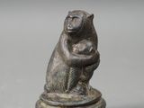 an old bronze figurine of a monkey holding a baby