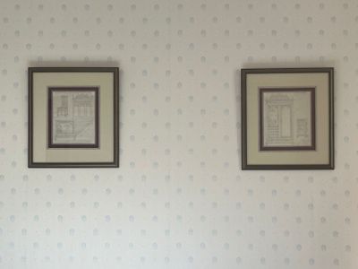deux tableaux encadrés accrochés au mur au-dessus d'un lit