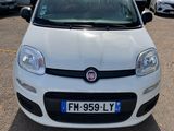 La petite voiture blanche est garée sur le parking, à côté d'autres voitures.