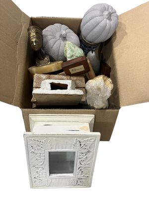 une boîte en carton remplie d'objets divers posée sur une surface blanche