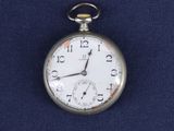une montre de poche en argent posée sur un tissu bleu