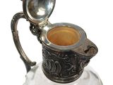 a silver and glass pitcher with a spoon in it