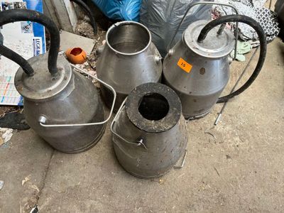 plusieurs vieilles casseroles en métal et une bouilloire posées par terre