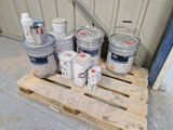 plusieurs seaux de peinture posés sur une palette devant un immeuble
