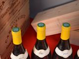 three bottles of wine sit in a wooden box on a red table