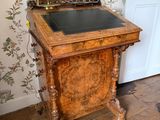un bureau en bois avec un plateau noir dans une pièce au papier peint à motifs floraux