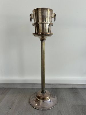 un seau à glace en argent posé sur un socle, sur un parquet