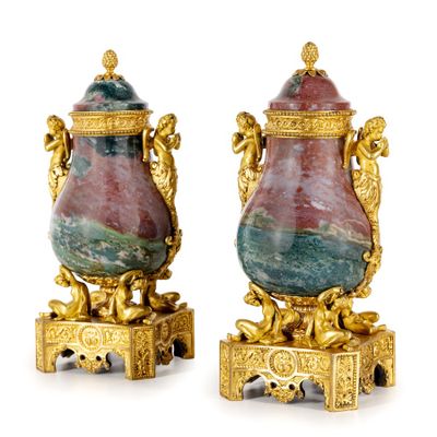 une paire de vases en or et en marbre sur socles, sur fond blanc