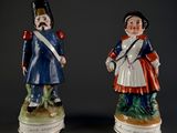 two figurines of men dressed in military uniforms are standing next to each other