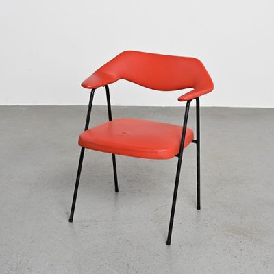une image représentant une chaise rouge aux pieds noirs dans une pièce