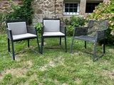 trois chaises et une table posées sur l'herbe, devant un bâtiment en pierre