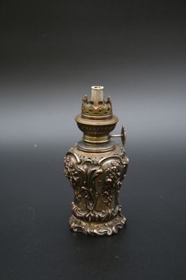 une lampe à huile en laiton ancien posée sur une surface noire