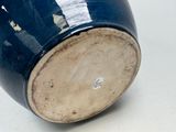 a close up of a blue vase on a white surface