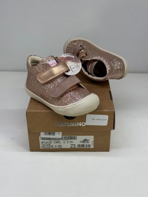 des chaussures de petite fille dans une boîte posée sur une surface blanche