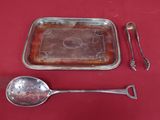 a silver tray with a spoon, spoon and spoon rest on a red table cloth
