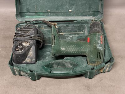 une mallette à outils verte contenant une perceuse filaire et une paire de chaussures