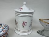 a white container with a floral design on it next to a bowl and a bowl with a lid