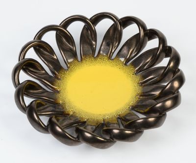 un bol en métal avec un centre jaune sur un fond blanc